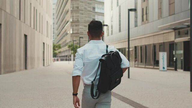 Young businessman walking through the business district. Back view