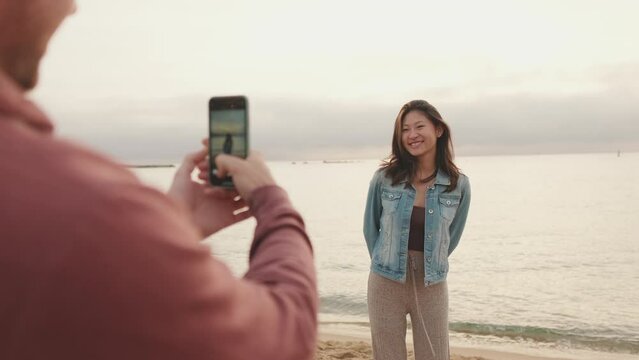 Man takes photo of woman on the shore