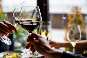 Close up of hands young couple toasting with glasses of red wine at restaurant