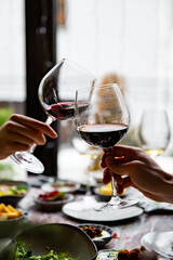 Close up of hands young couple toasting with glasses of red wine at restaurant