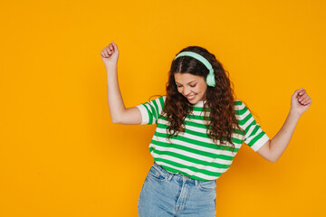 Cheerful girl dancing while listening music with headphones isolated