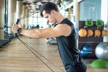 Man pulling cables. Handsome athlete male lifting up and push up on sling to maintain muscle, build strength, flexibility at fitness or gym health club.
