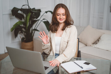 Happy young business woman employee, hr manager having remote online work hybrid meeting or distance job interview waving hand looking at laptop during virtual video conference call in office.