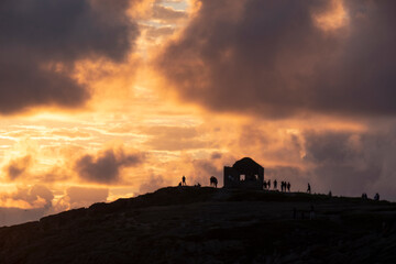 Silouette of a ruined house and some people over a hill at sunset