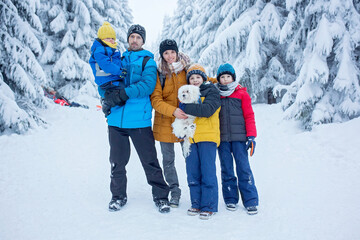 Fototapeta na wymiar Happy family witn children, hiking in mountains wintertime, lots of snow, beautiful winter forest