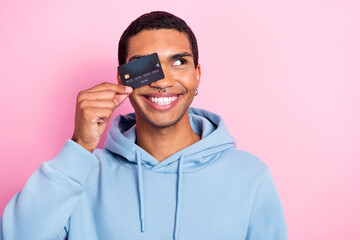 Photo of handsome good mood man wear blue sweatshirt cover face eye credit card demonstrate promo...