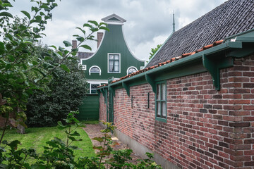An empty yard in a circle of old traditional Dutch houses, framed by tree branches and hedges. - 564677169