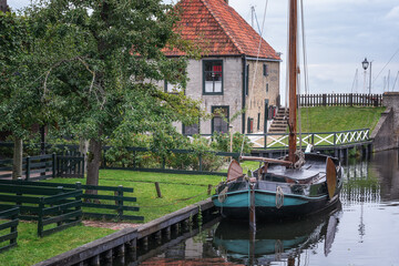 Traditional Dutch fishing boat with picturesque fishermen's cottages in the background. - 564677332