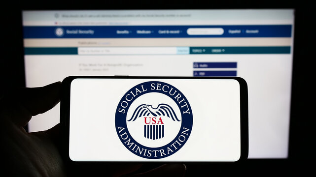 Stuttgart, Germany - 01-22-2023: Person holding cellphone with seal of US Social Security Administration (SSA) on screen in front of webpage. Focus on phone display.