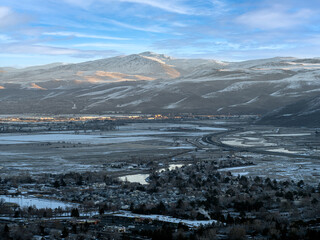 Fototapeta na wymiar Aerial view of East Sparks Nevada along Veterans Parkway during winter with Snowcapped Mountains, frozen rivers and lakes and early morning traffic.