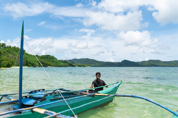 Obraz premium fisherman dragging his boat into the sea to go fishing , philippines islands