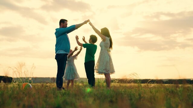 Teamwork Happy Family Shows House With Their Hands, Symbol Of Safety, Comfort For Child, Sunset. Happy Family Mother Father Daughter, Son, Kid, Dream To Build House, Mortgage For Family. Parents Child