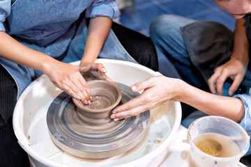 Close up hands make dishes from ceramic clay working on potters wheel traditional pottery craft