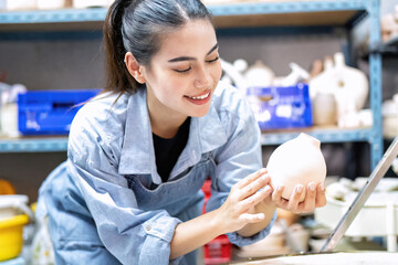 Pot making women arrange the ceramic clay pot on the shelf in pottery workshop