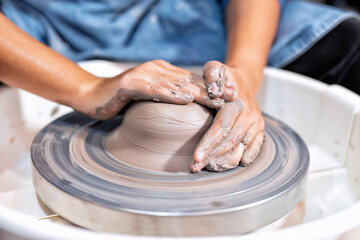 Close up hands make dishes from ceramic clay working on potters wheel traditional pottery craft