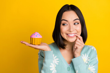Photo of satisfied good mood woman with bob hairdo dressed blue pullover look at cake finger mouth isolated on yellow color background