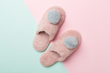 Soft pink slippers on color background, top view