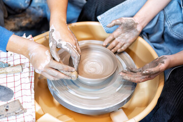 Close up hands make dishes from ceramic clay working on potters wheel traditional pottery craft
