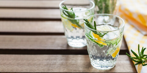 Infused water with a lemon, cucumber and rosemary in a glasses on a table. Copy space