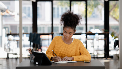 American teenage woman sitting in office with laptop, she is a student studying online with laptop at home, university student studying online, online web education concept.