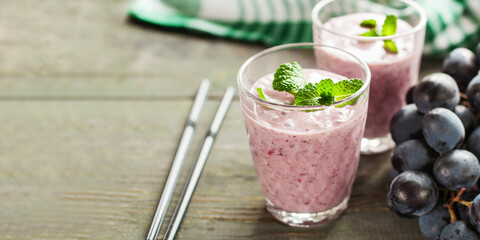 Milkshake or smoothie with apple, banana and grapes in a glasses on a table. Copy space
