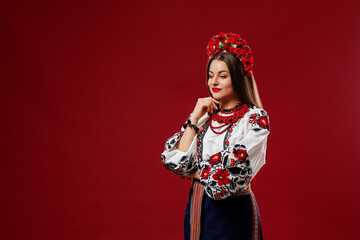 Portrait of ukrainian woman in traditional ethnic clothing and floral red wreath on viva magenta...