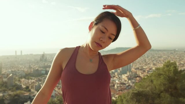 Young woman stretches her neck muscles while standing on an observation deck