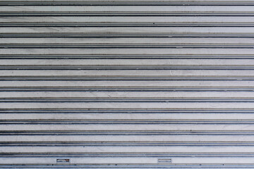 The texture of closed grey metallic roller shutter door in front of the factory