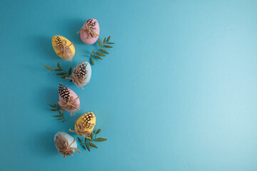 Decorated Easter eggs and quail spotted eggs in spring decor on a blue background copy space