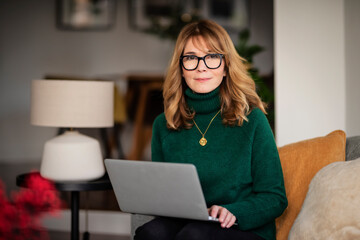 Casual woman sitting at home and using laptop for work