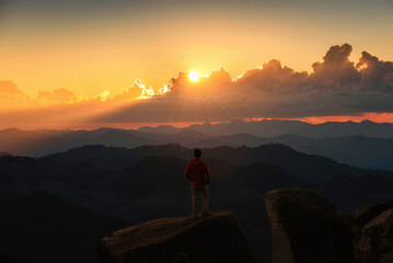 Hiker man standing and looking the view on top of mountain during sunset in tropical rainforest at national park