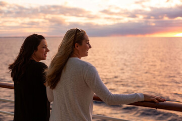 Fototapeta premium Two Attractive middle-aged women enjoying the sunset view from the deck of a cruise ship while on a vacation together in the Caribbean