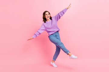 Fototapeta na wymiar Full length photo of adorable sweet girl dressed purple pullover walking arms sides having fun isolated pink color background