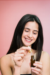 Smiling woman with bottle of serum