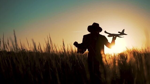 Happy girl with oy in natural park. Child runs on grass with an airplane. Chidhood dream. Happy baby girl with toy airplane at sunset. Child runs on grass in field. Dream travel concept