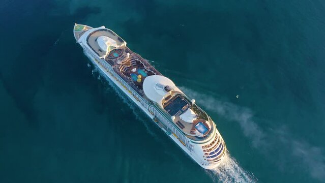 Cruise ship sailing across The Mediterranean sea - Aerial footage. Aerial view of a beautiful white cruise liner in a sunny day. Luxury cruise in the ocean sea concept tourism travel. 