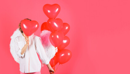 Valentines day. Angel woman in angelic wings with heart shaped balloons. Copy space.