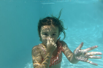child swimming underwater with bubbles