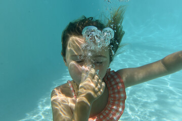 child swimming underwater with bubbles