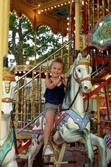 smiling little girl on a horse in a carousel