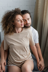 young woman with closed eyes sitting with bearded boyfriend.