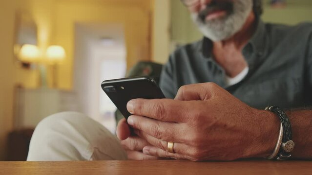 Close-up of an elderly man's hands typing on mobile phone