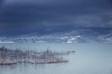 Krajobraz wodny nad jeziorem. Zimowa, śnieżna i mroźna sceneria. Styczniowa przyroda.	