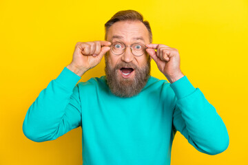 Photo portrait of nice retired man touch eyewear astonished reaction wear trendy aquamarine clothes isolated on yellow color background