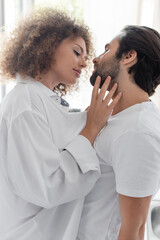 curly and young woman in white shirt seducing bearded man in kitchen.
