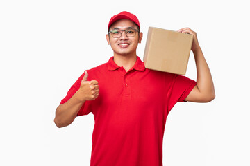 Smiling asian courier delivery man in red cap and t-shirt hold package on shoulder, make thumb-up
