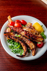Grilled octopus. Prepared in traditional Italian style: fried in olive  oil, garlic and seasoned with salt and pepper. Served over bed of arugula salad, cherry tomatoes and seasoned with fresh herbs.