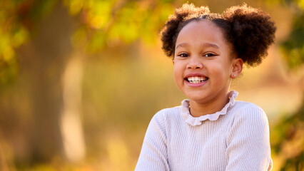 Head And Shoulders Portrait Of Smiling Young Girl Outdoors In Countryside