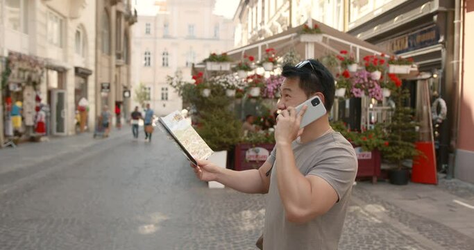 Korean man with a map talking by phone in a city
