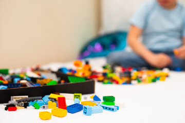 Color blocks of a small constructor on a children's bed in the background a boy in a blue T-shirt sits